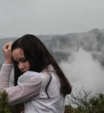 woman in white sweater covering her face with her hands