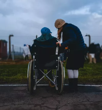 woman standing near person in wheelchair near green grass field