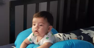 boy in blue and white shirt lying on bed