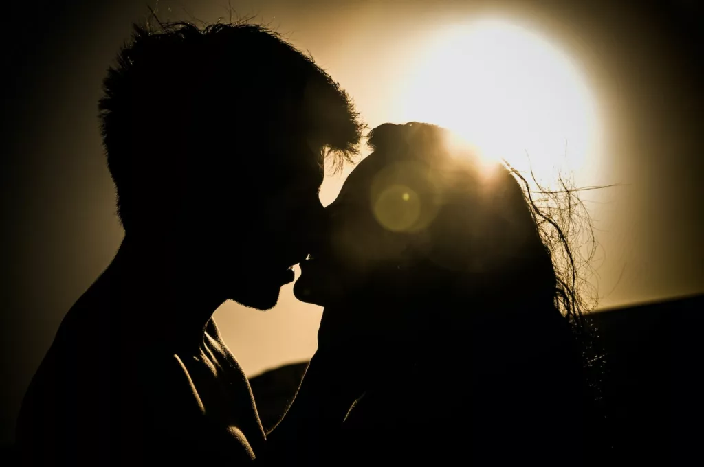 man and woman kissing under the sun