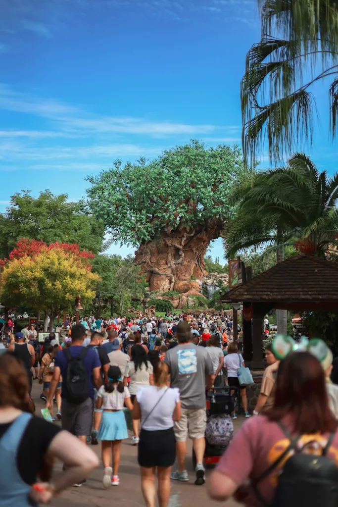 a crowd of people walking down a street next to a tree