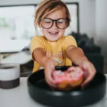 girl in yellow crew neck t-shirt wearing eyeglasses sitting on chair